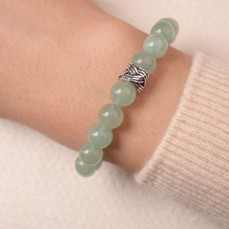 A hand wearing the Prehnite and Amethyst bracelet, showing off the calming green and purple beads, complemented by the silver spacer.
