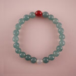 Green chalcedony bracelet with a red agate bead and a white chalcedony bead, photographed under soft daylight.