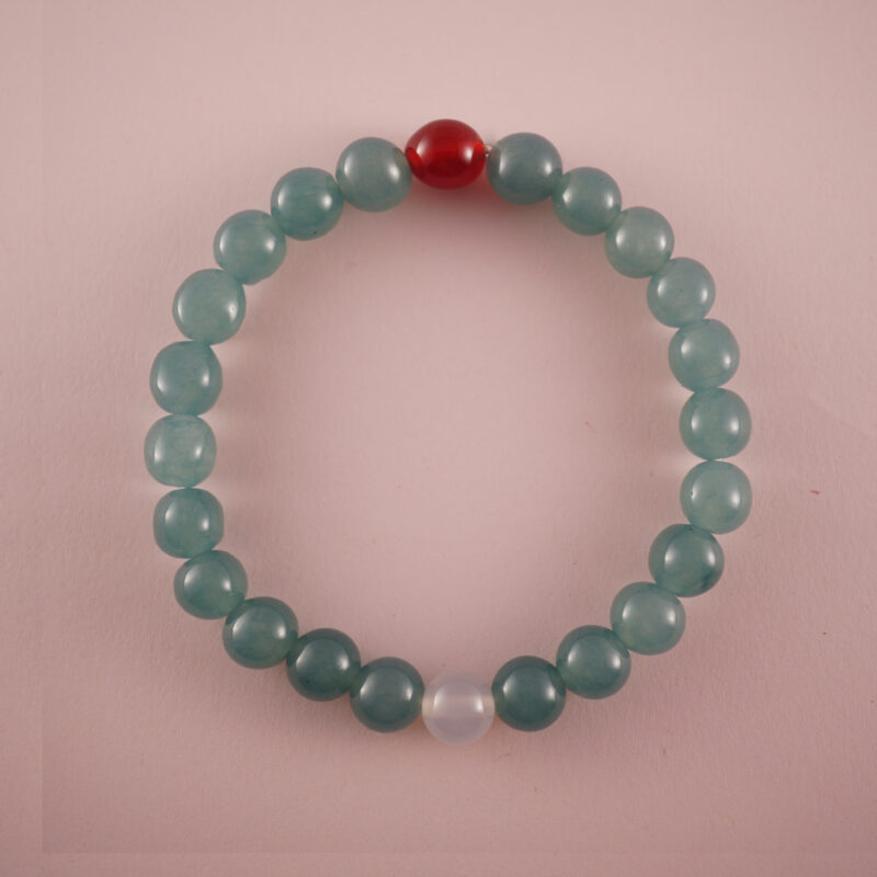 Green chalcedony bracelet with a red agate bead and a white chalcedony bead, photographed under soft daylight.