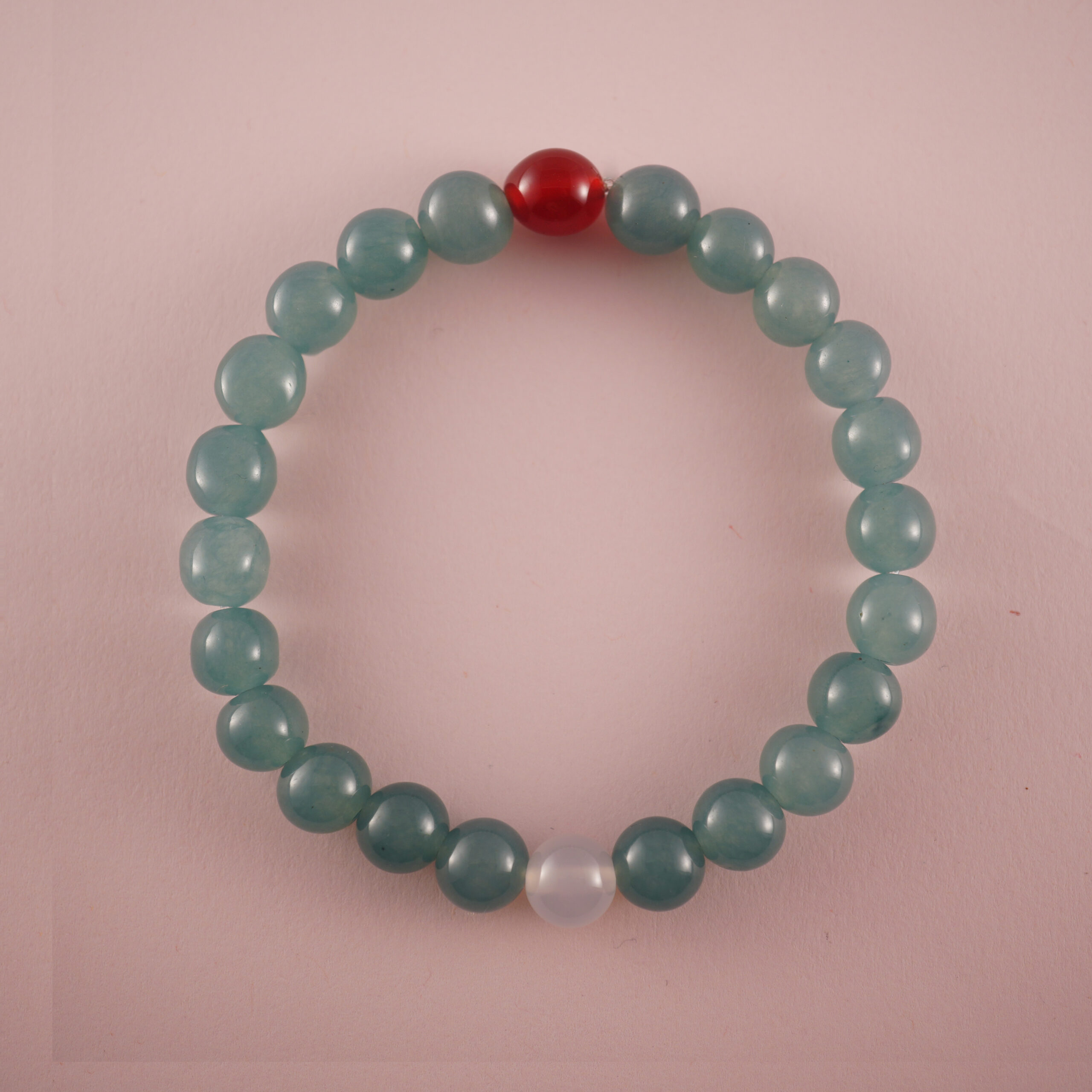 green-chalcedony-bracelet-with-red-agate-and-white-chalcedony Green chalcedony bracelet with a red agate bead and a white chalcedony bead, photographed under soft daylight.