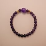 Amethyst and black tourmaline bracelet with gold accent beads, photographed under soft daylight on a neutral background.