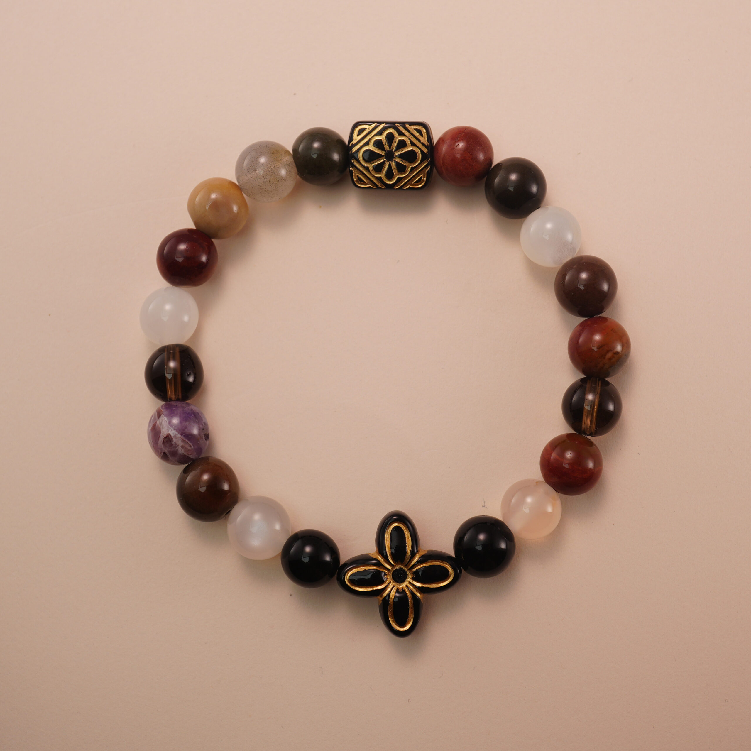 multicolor-gemstone-bracelet-with-black-gold-bead Multicolor gemstone bracelet with a black and gold patterned bead, photographed under soft daylight on a neutral background.