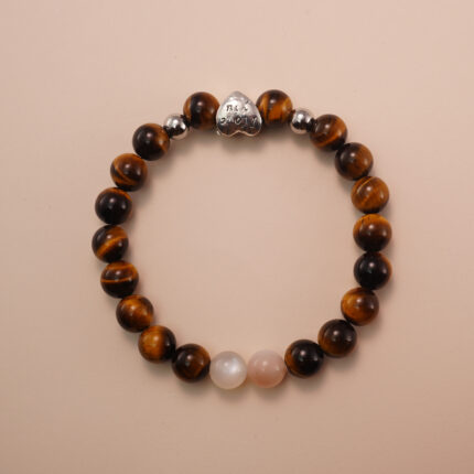 Tiger’s eye and moonstone bracelet with a silver heart accent bead, photographed under soft daylight to highlight the warm golden and soft white tones.