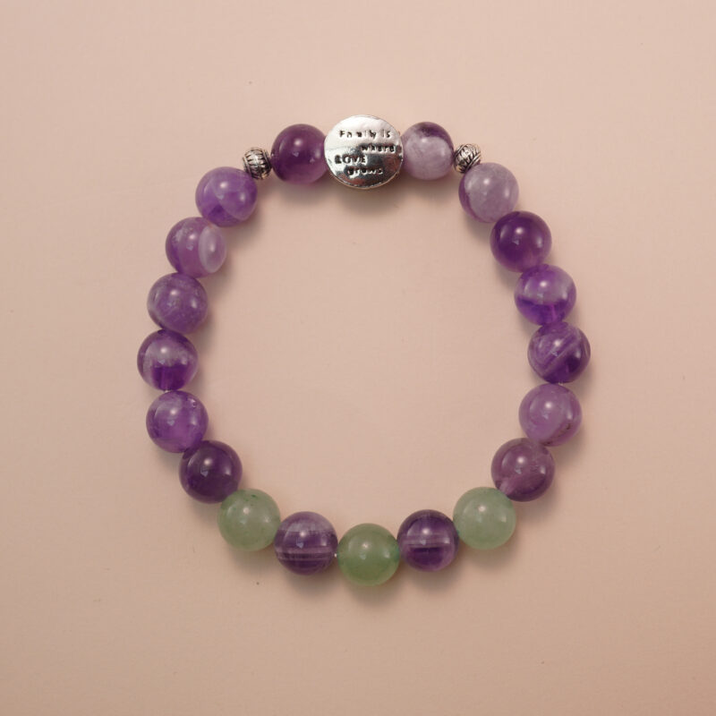 Amethyst and prehnite bracelet with a silver accent bead, photographed under soft daylight to highlight the calming purple and gentle green tones.