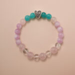 Kunzite, amazonite, and clear quartz bracelet with a silver heart accent bead, photographed under soft daylight to highlight the pastel purple, aqua green, and translucent white tones.