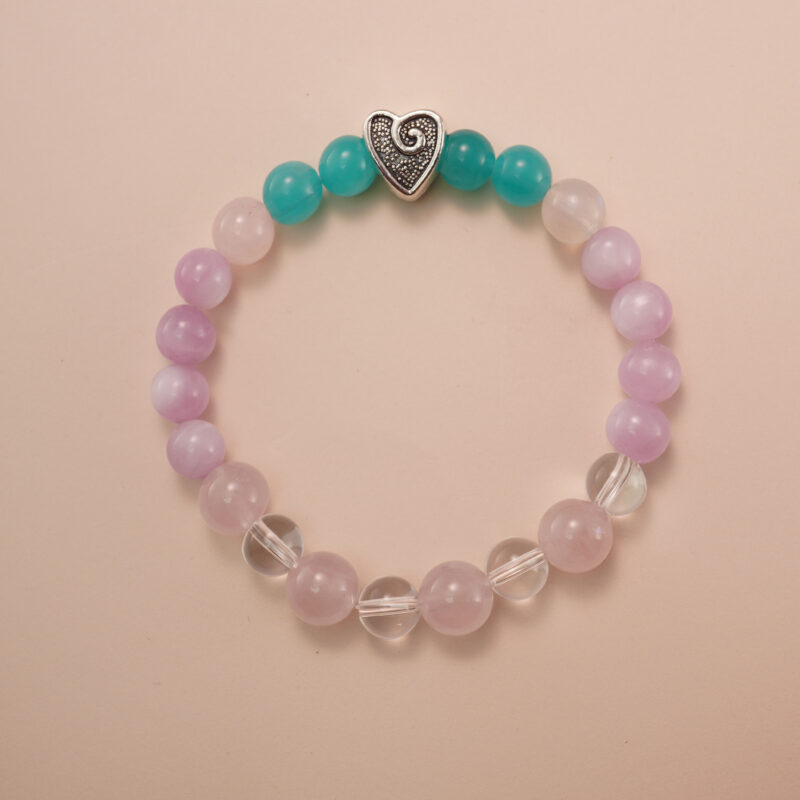 Kunzite, amazonite, and clear quartz bracelet with a silver heart accent bead, photographed under soft daylight to highlight the pastel purple, aqua green, and translucent white tones.