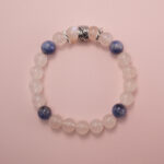Moonstone and kyanite bracelet photographed under soft daylight on a pink background, highlighting the milky white glow of moonstone and the deep blue tones of kyanite.