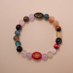 Multicolor gemstone bracelet featuring a mix of natural stones in red, blue, yellow, pink, and brown tones, photographed under soft daylight on a neutral background.