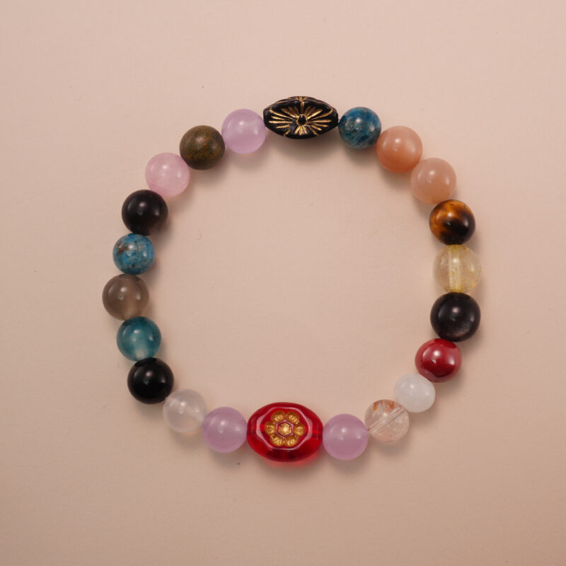 Multicolor gemstone bracelet featuring a mix of natural stones in red, blue, yellow, pink, and brown tones, photographed under soft daylight on a neutral background.