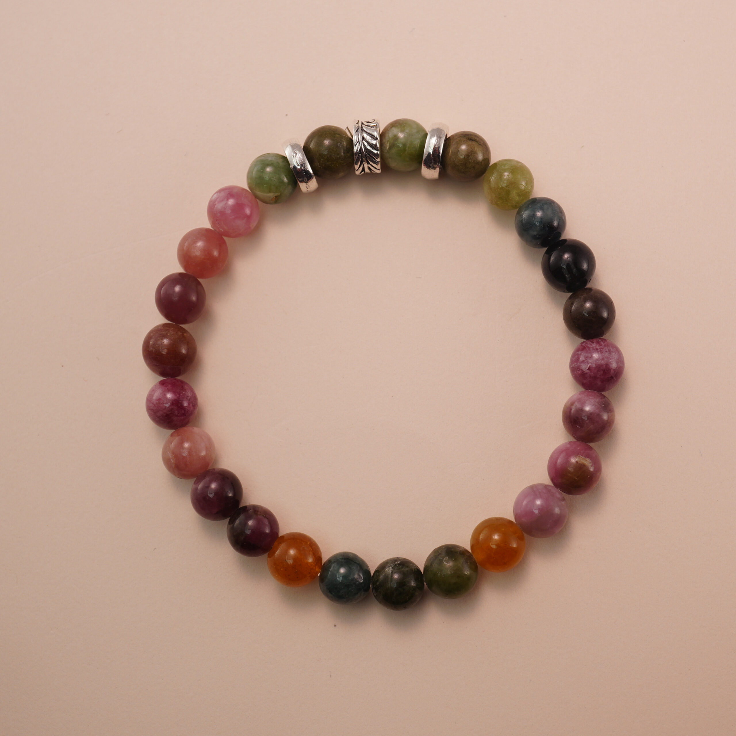 multicolor-tourmaline-bracelet-natural-light Multicolor tourmaline bracelet photographed under soft daylight on a neutral background, showing the natural gradient of pink, green, and brown gemstones.