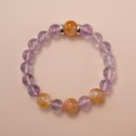 Amethyst and citrine bracelet photographed under soft natural light on a neutral background, showing the gentle purple and golden-yellow gemstone combination.