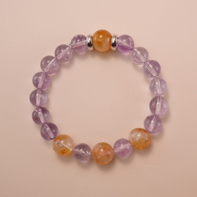 Amethyst and citrine bracelet photographed under soft natural light on a neutral background, showing the gentle purple and golden-yellow gemstone combination.
