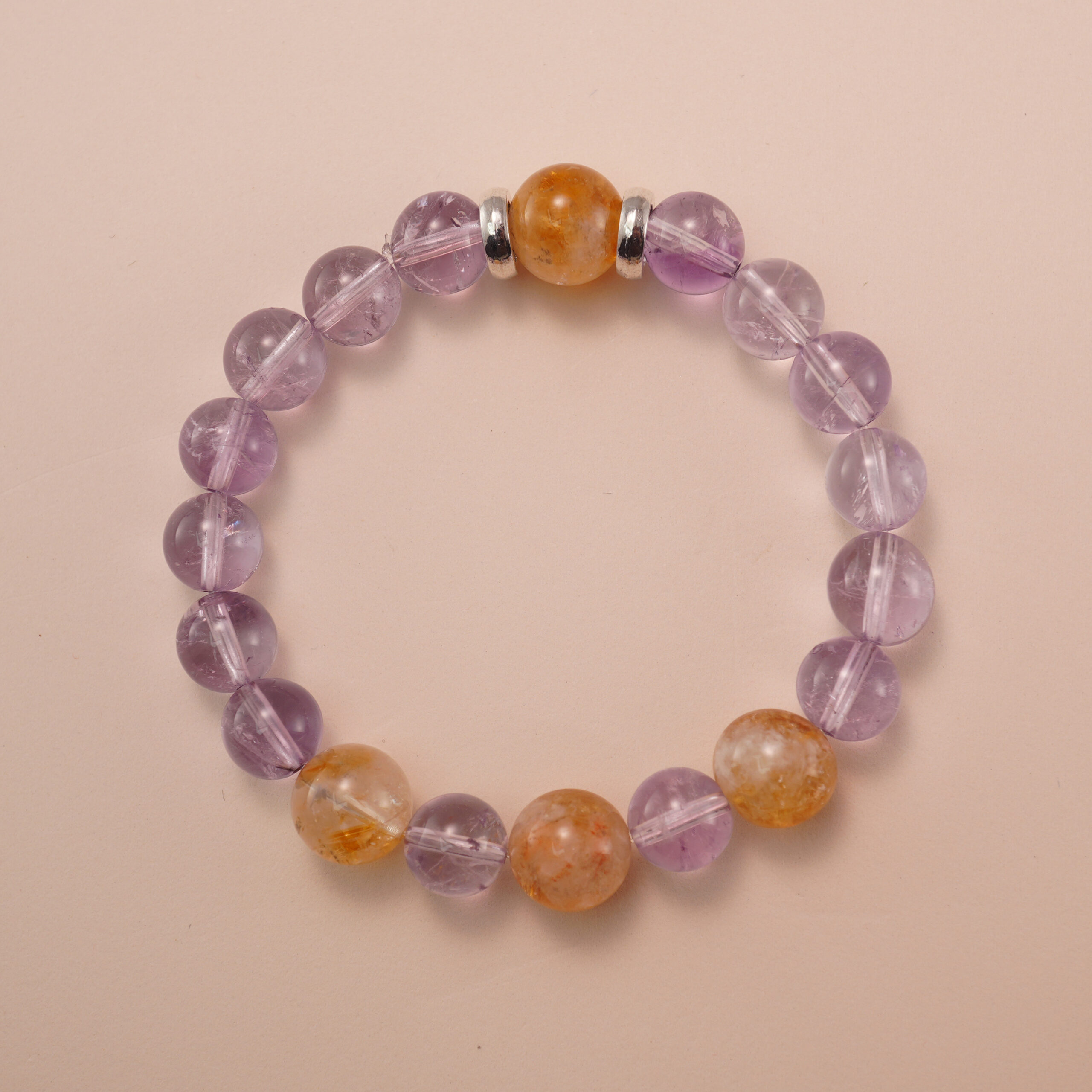 amethyst-citrine-bracelet-natural-light Amethyst and citrine bracelet photographed under soft natural light on a neutral background, showing the gentle purple and golden-yellow gemstone combination.