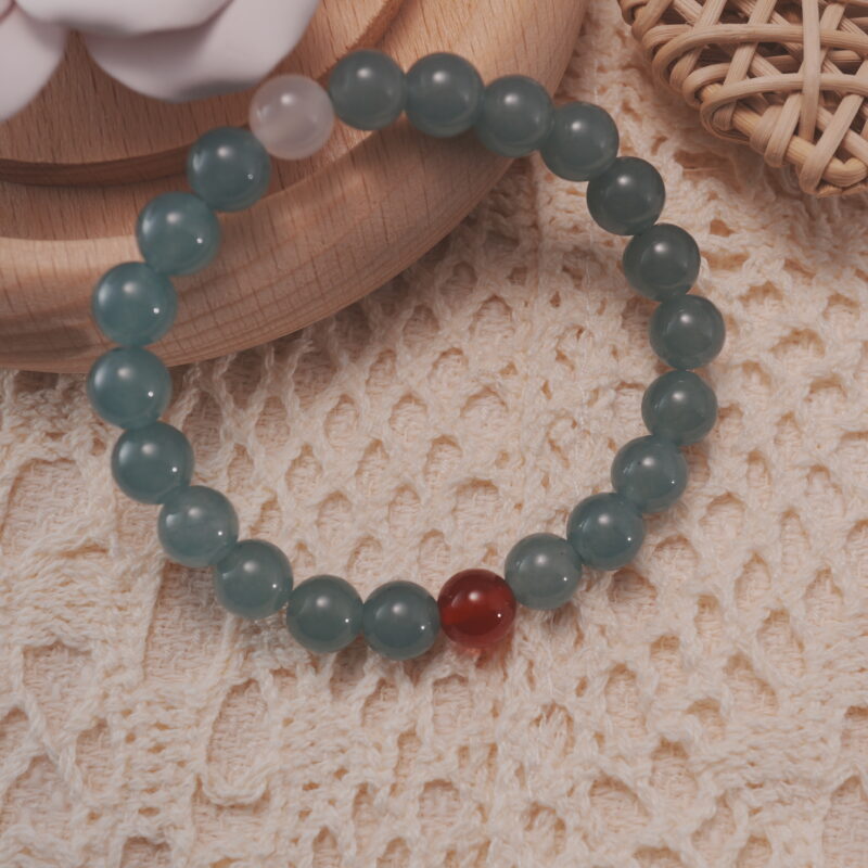 Green chalcedony bracelet with red agate and white chalcedony beads, displayed in a natural lifestyle setting under soft daylight.
