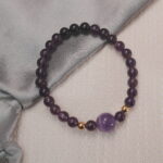 Amethyst and black tourmaline bracelet displayed in a natural lifestyle setting under daylight, highlighting the balance between protective black tones and calming violet hues.