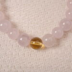 Close-up of rose quartz and citrine beads, showing natural texture and silver heart charm detail.
