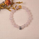 Lifestyle photo of rose quartz and citrine bracelet with silver heart charm, placed beside dried flowers.