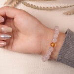 Model wearing rose quartz and citrine bracelet with silver heart charm, showcasing romantic and healing energy.