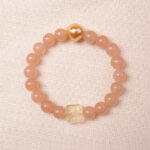 Peach moonstone bracelet with citrine and gold heart bead, symbolizing love, abundance, and gentle feminine energy.