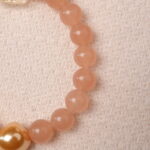 Close-up of peach moonstone bracelet showing natural gemstone texture and gold heart bead detail.