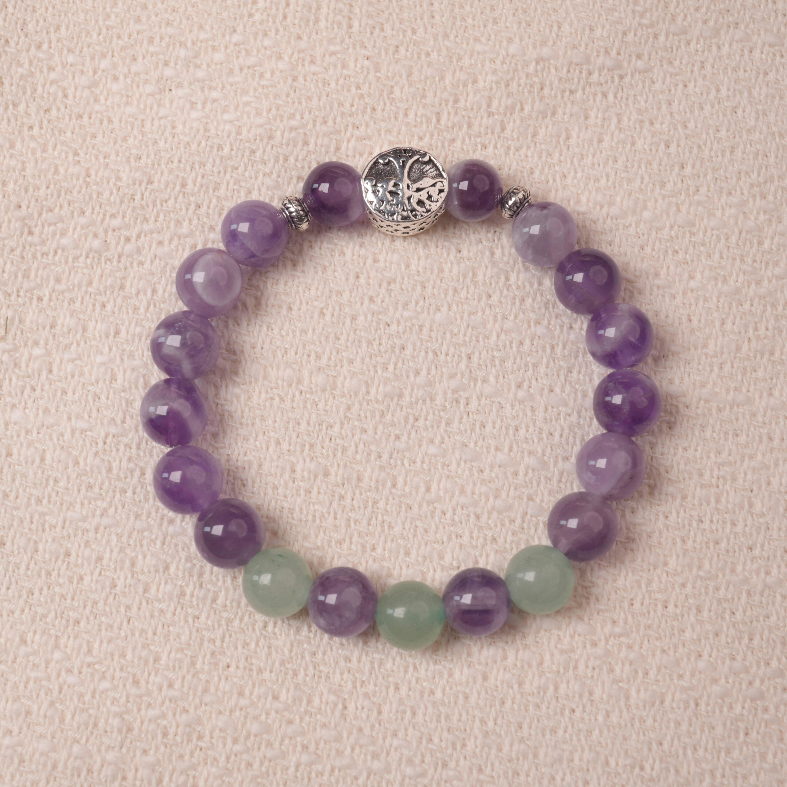 amethyst-prehnite-bracelet-with-silver-bead Amethyst and prehnite bracelet with a silver accent bead, photographed under soft daylight to highlight the calming purple and gentle green tones.