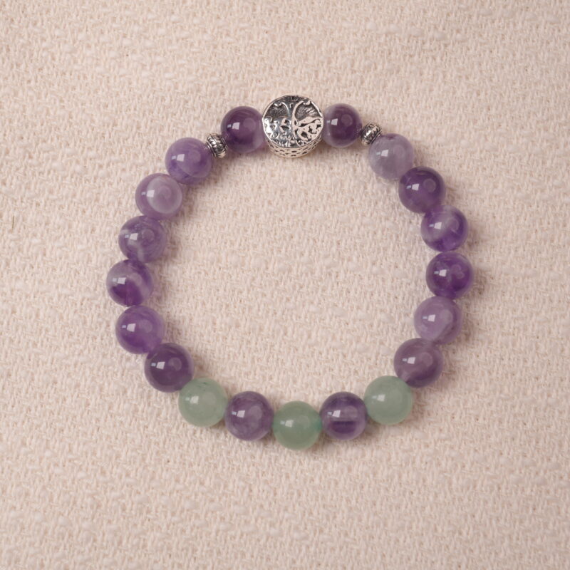 Amethyst and prehnite bracelet with a silver accent bead, photographed under soft daylight to highlight the calming purple and gentle green tones.