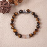 Lifestyle photo of tiger eye bracelet placed on beige fabric with warm earthy tones.
