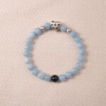 Aquamarine bracelet with silver heart charm and black accent bead, symbolizing calmness and clear communication.