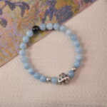 Lifestyle photo of aquamarine bracelet placed on soft fabric beside an art book.
