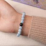 Back view of aquamarine bracelet with smooth round beads and a black accent stone.