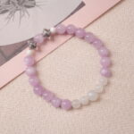 Lifestyle photo of kunzite and moonstone bracelet placed beside a pink art book.