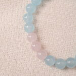 Close-up of aquamarine and rose quartz beads showing glossy polish and natural pastel tones.