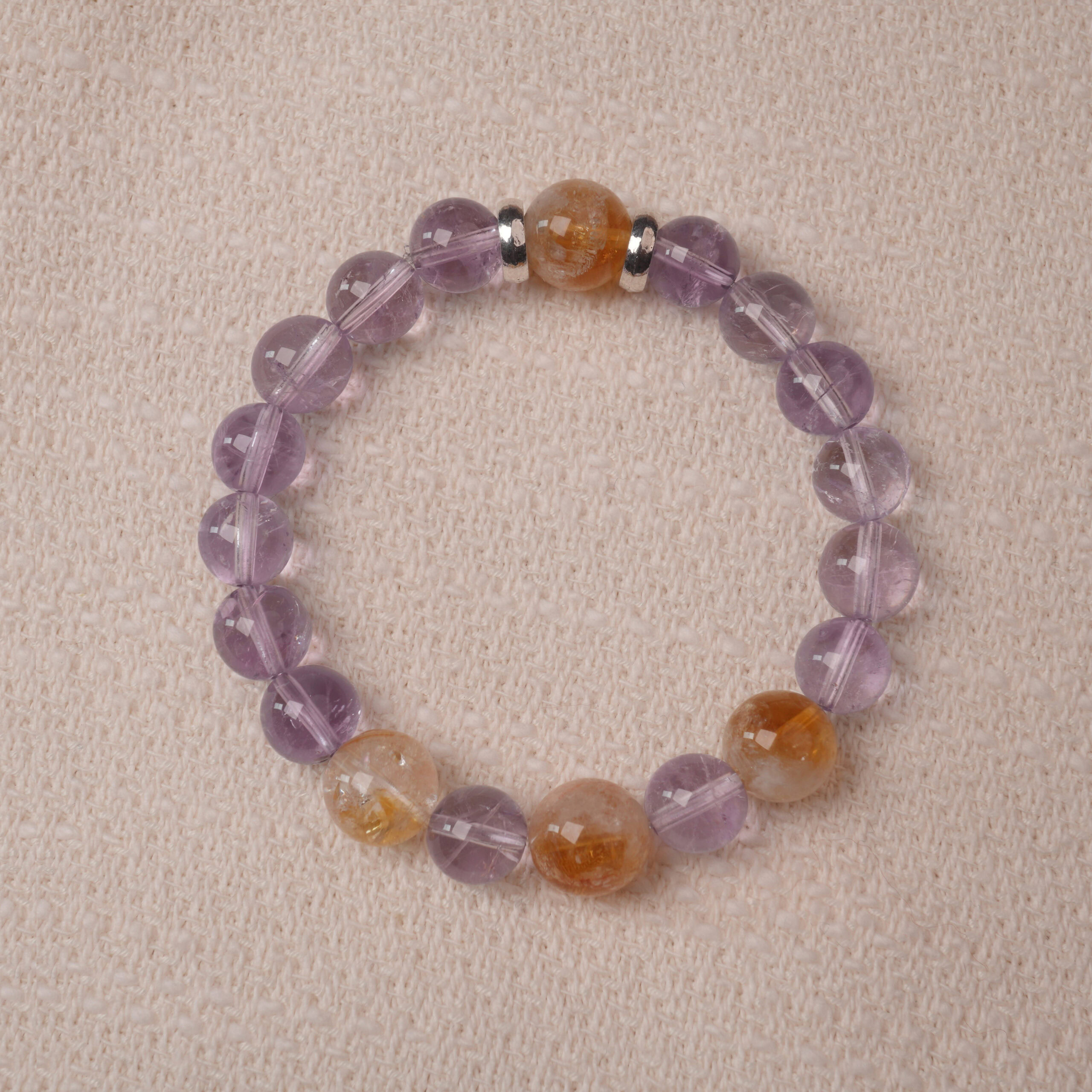 amethyst-citrine-bracelet-hexagonal-crystals A close-up shot of an Amethyst and Citrine bracelet, featuring hexagonal-cut crystals in shades of purple and golden yellow. The bracelet is designed with silver spacers to accentuate the striking contrast between the two stones, giving it a sophisticated and vibrant look.