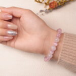 Back view of rose quartz bracelet with silver bow charm, radiating feminine energy.