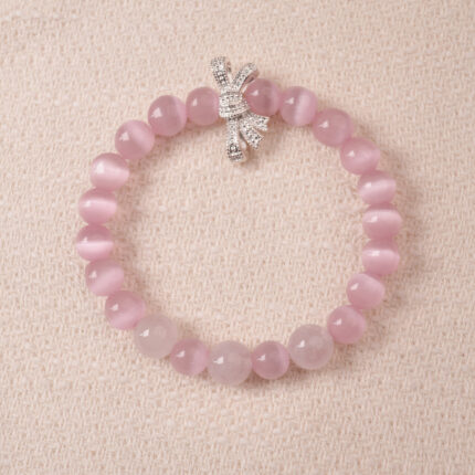 Rose quartz bracelet with silver bow charm, symbolizing love, tenderness, and self-care.