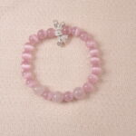 Rose quartz bracelet with silver bow charm, symbolizing love, tenderness, and self-care.