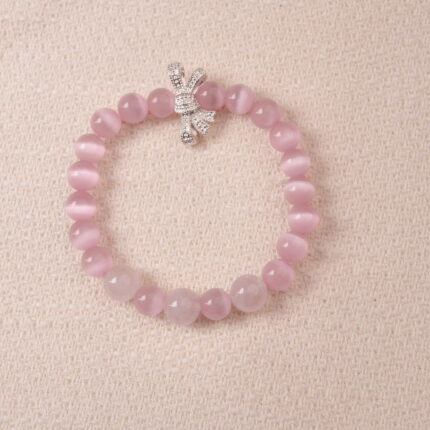 Rose quartz bracelet with silver bow charm, symbolizing love, tenderness, and self-care.