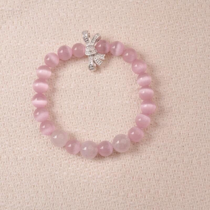 Rose quartz bracelet with silver bow charm, symbolizing love, tenderness, and self-care.
