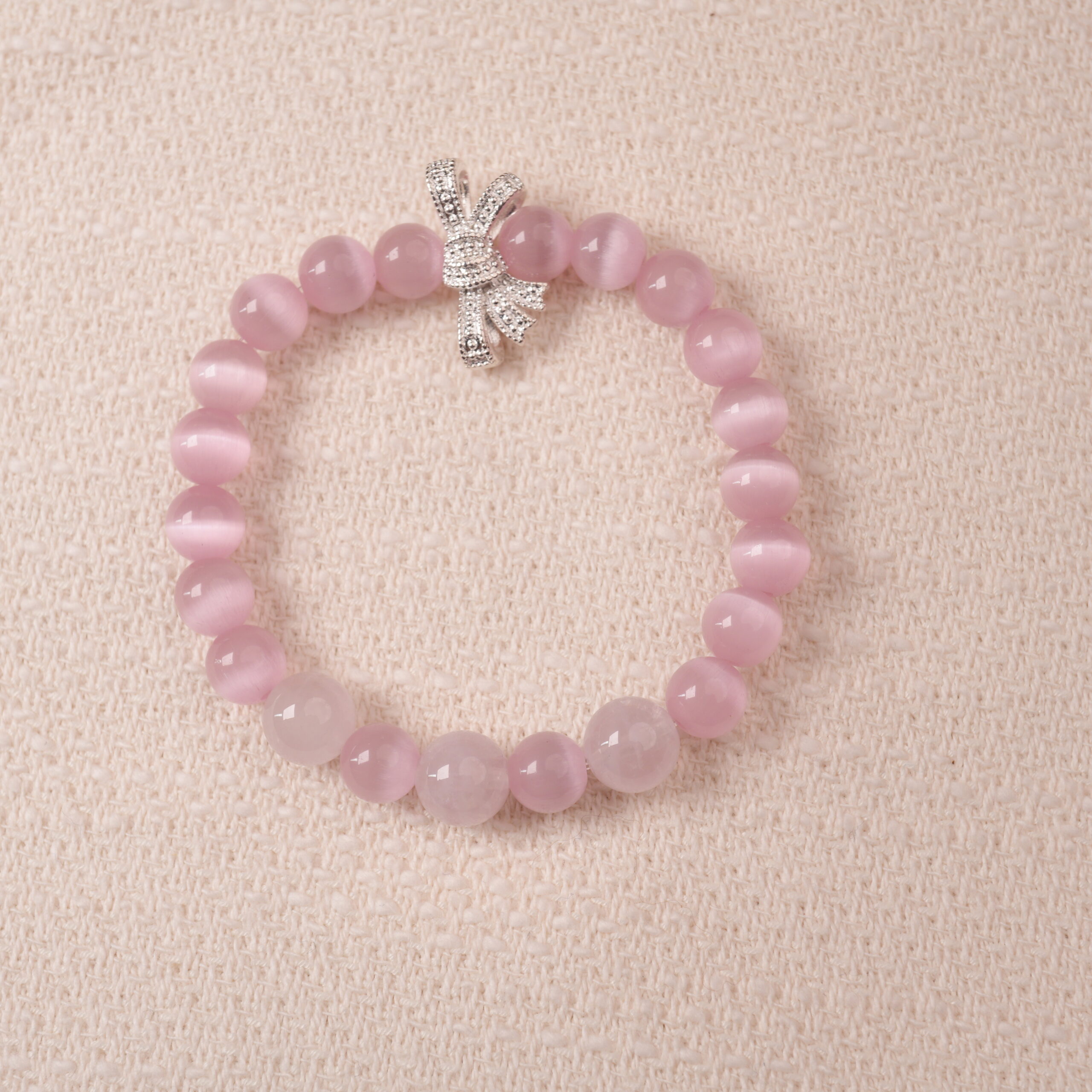 rose-quartz-bow-charm-bracelet-main.jpg Rose quartz bracelet with silver bow charm, symbolizing love, tenderness, and self-care.