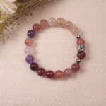 Lifestyle photo of strawberry quartz and amethyst bracelet placed on fabric, radiating warmth and gentle energy.