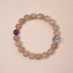 Moonstone, Amethyst, and Strawberry Quartz bracelet with a silver flower accent bead, designed for tranquility and emotional healing.