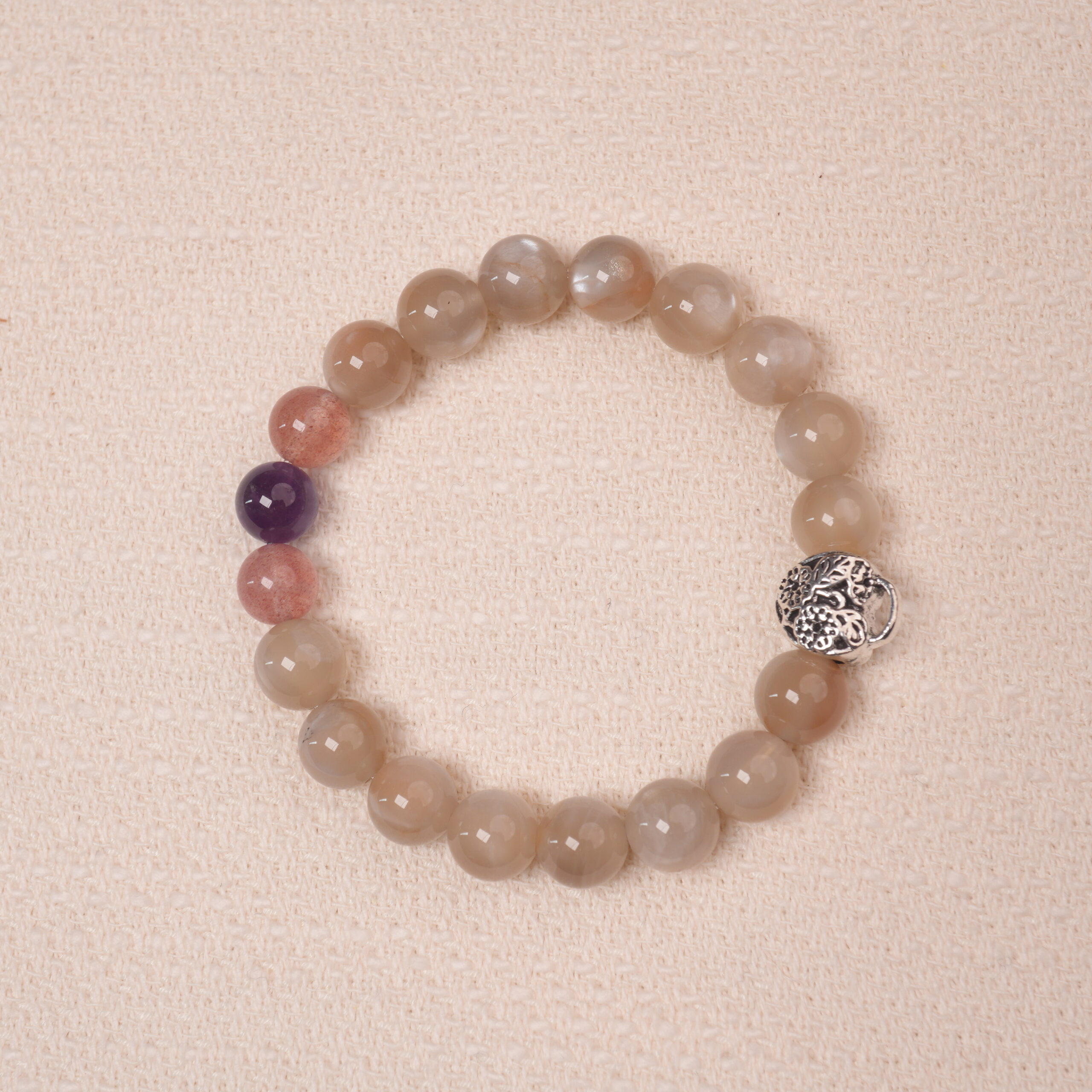 moonstone-amethyst-strawberry-quartz-bracelet-main Moonstone, Amethyst, and Strawberry Quartz bracelet with a silver flower accent bead, designed for tranquility and emotional healing.