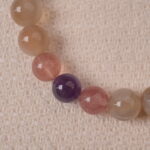 Close-up of Moonstone, Amethyst, and Strawberry Quartz bracelet, highlighting the smooth beads and the silver flower accent.