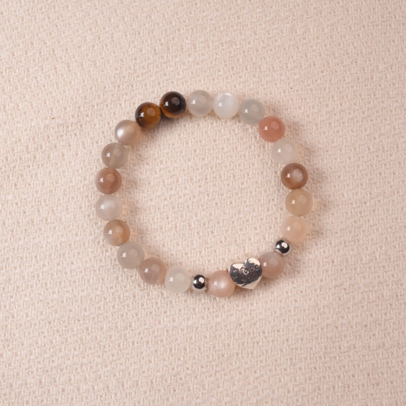 Rainbow moonstone and tiger’s eye bracelet with a silver heart bead engraved with “I love you,” photographed under soft daylight to highlight the iridescent white and golden-brown hues.