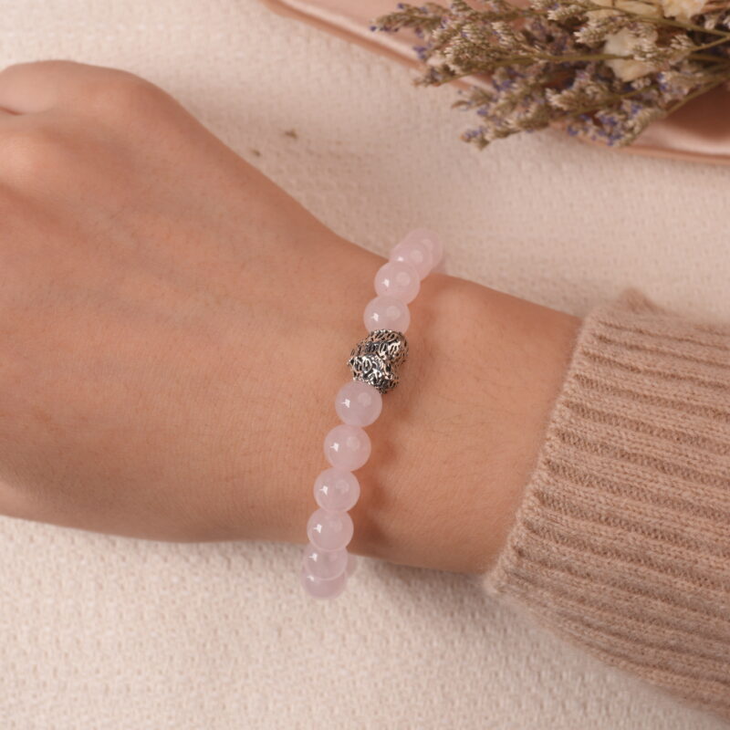 Model wearing Tranquil Love bracelet, showcasing the beautiful combination of soft pink and purple beads with a heart-shaped silver charm.
