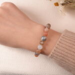 A model wearing the multicolor Moonstone bracelet on their wrist. The soft pastel colors and silver accents create a peaceful and elegant look that complements any outfit.
