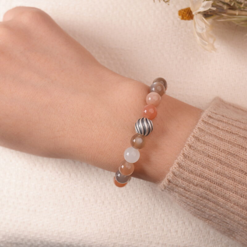 A model wearing the multicolor Moonstone bracelet on their wrist. The soft pastel colors and silver accents create a peaceful and elegant look that complements any outfit.