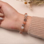 A model wearing the multicolor Moonstone bracelet on their wrist. The soft pastel colors and silver accents create a peaceful and elegant look that complements any outfit.