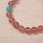 Close-up detail of the Strawberry Quartz beads and Angelite stones, showcasing the beautiful smooth texture and the heart-shaped silver charm at the center, adding a delicate touch to the bracelet.