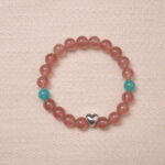 A beautiful Strawberry Quartz bracelet featuring heart-shaped silver accents and Angelite beads, creating a soothing and romantic look. The bracelet combines the healing properties of Strawberry Quartz and Angelite with a delicate silver heart charm.